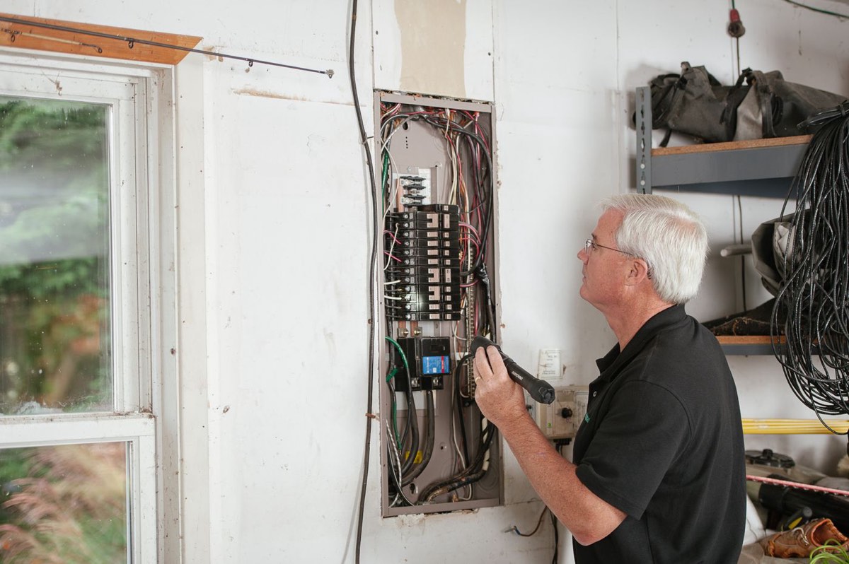 An electrician inspecting a home electrical panel